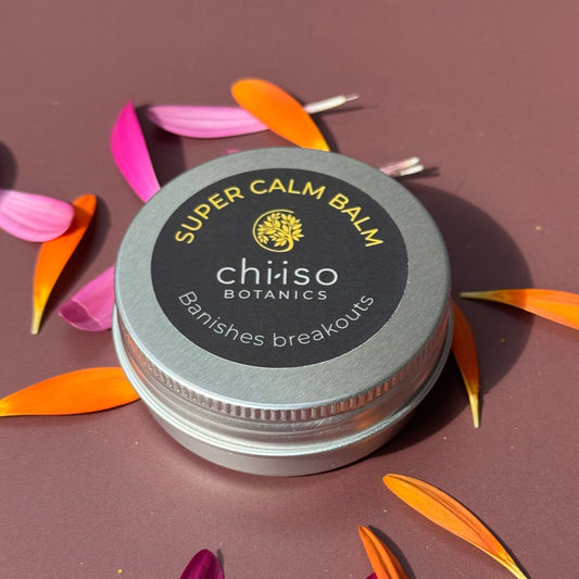 30ml tin of face balm with flower petals scattered around it.